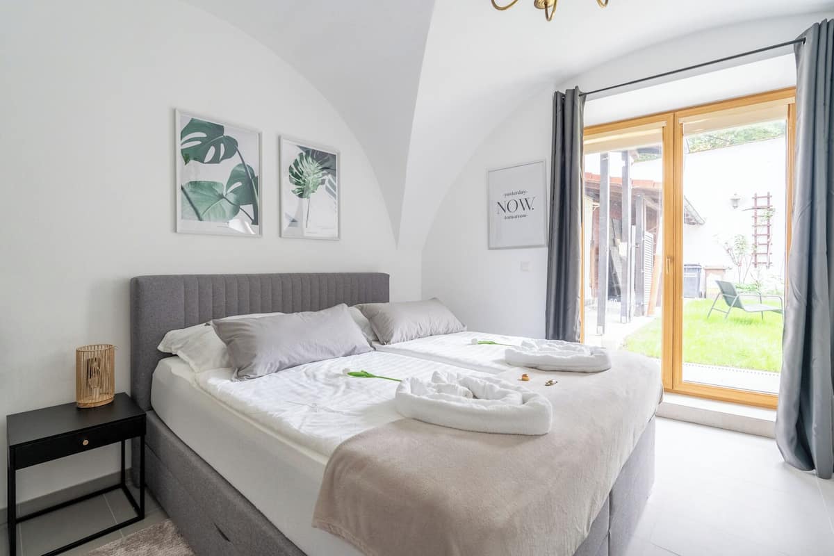 Ein modernes Schlafzimmer mit einem großen Bett, einem Nachttisch und Blick ins Freie.