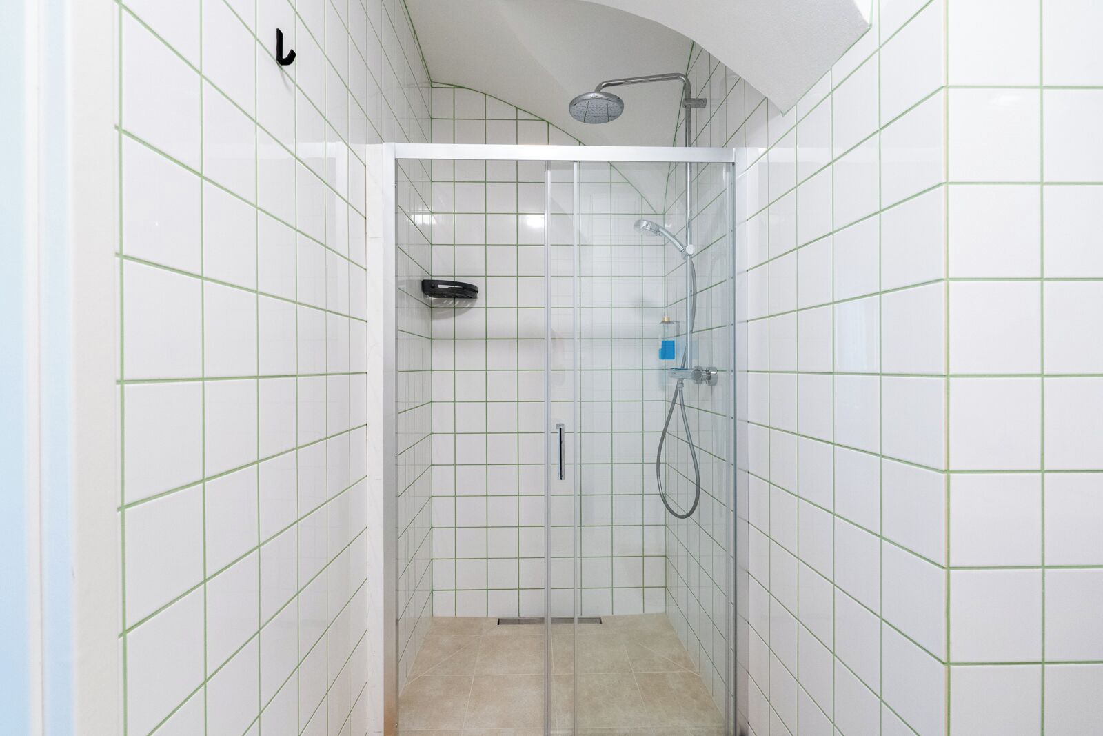 A small, enclosed shower area with white tiled walls and a glass door.