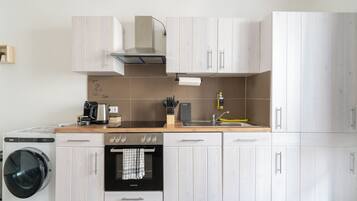 Une cuisine moderne équipée d’un lave-linge, d’un four et d’une machine à café.