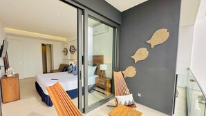 Ett modernt hotellrum med en stor säng, en trästol, ett litet bord och en glasdörr som leder ut till en balkong.