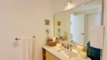 Une salle de bain moderne avec un grand miroir, un lavabo et un porte-serviettes.