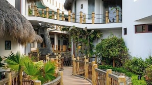 Un resort con una terraza de madera, edificios con techo de paja y abundante vegetación.