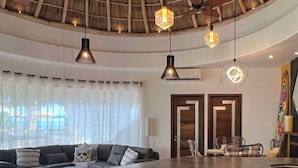 Una cocina moderna con una isla curva, iluminaci ón colgante y un comedor con sillas.
