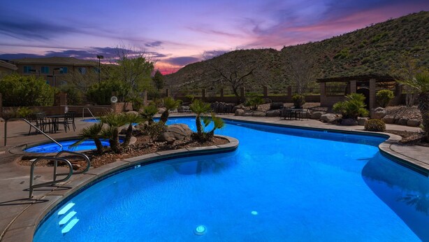 A swimming pool with a view of a hilly landscape and a sunset.