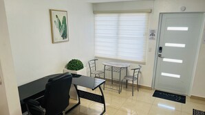 A small office space with a desk, two chairs, a potted plant, and a door with a window.