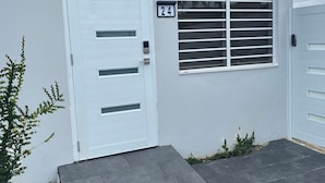 A white house with a number 24 sign, a white door, and a window with horizontal blinds.