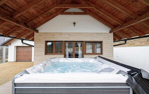 A hot tub under a wooden roof with a stone wall and windows. - 2 bedroom stunning home in Krasno (Krasno)