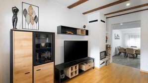A modern living room with a wooden cabinet, a flat-screen TV, and a fireplace.