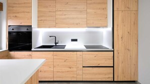 A modern kitchen with wooden cabinets, a black oven, and a white countertop.