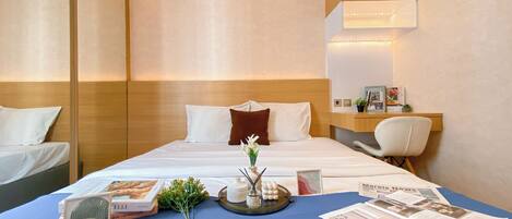 A hotel room with a bed, bedside table, and a desk with a chair.