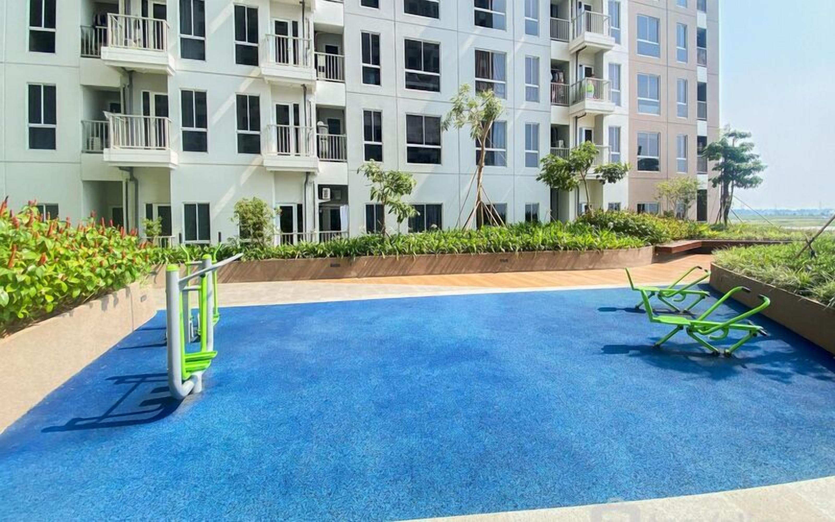 A swimming pool with a blue surface, surrounded by a low wall and greenery.
