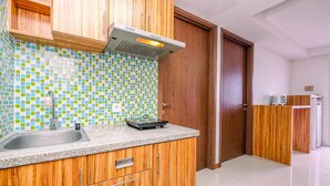 A kitchen with wooden cabinets, a tiled backsplash, a stainless steel sink, and a built-in range hood.