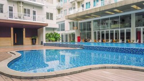 A swimming pool with a tiled edge, surrounded by a wooden deck.
