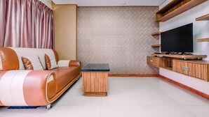 A modern living room with a sofa, TV stand, and built-in shelves.