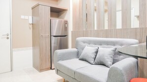 Eine moderne Küche mit grauem Sofa, einem Edelstahlkühlschrank und einem Glastisch.