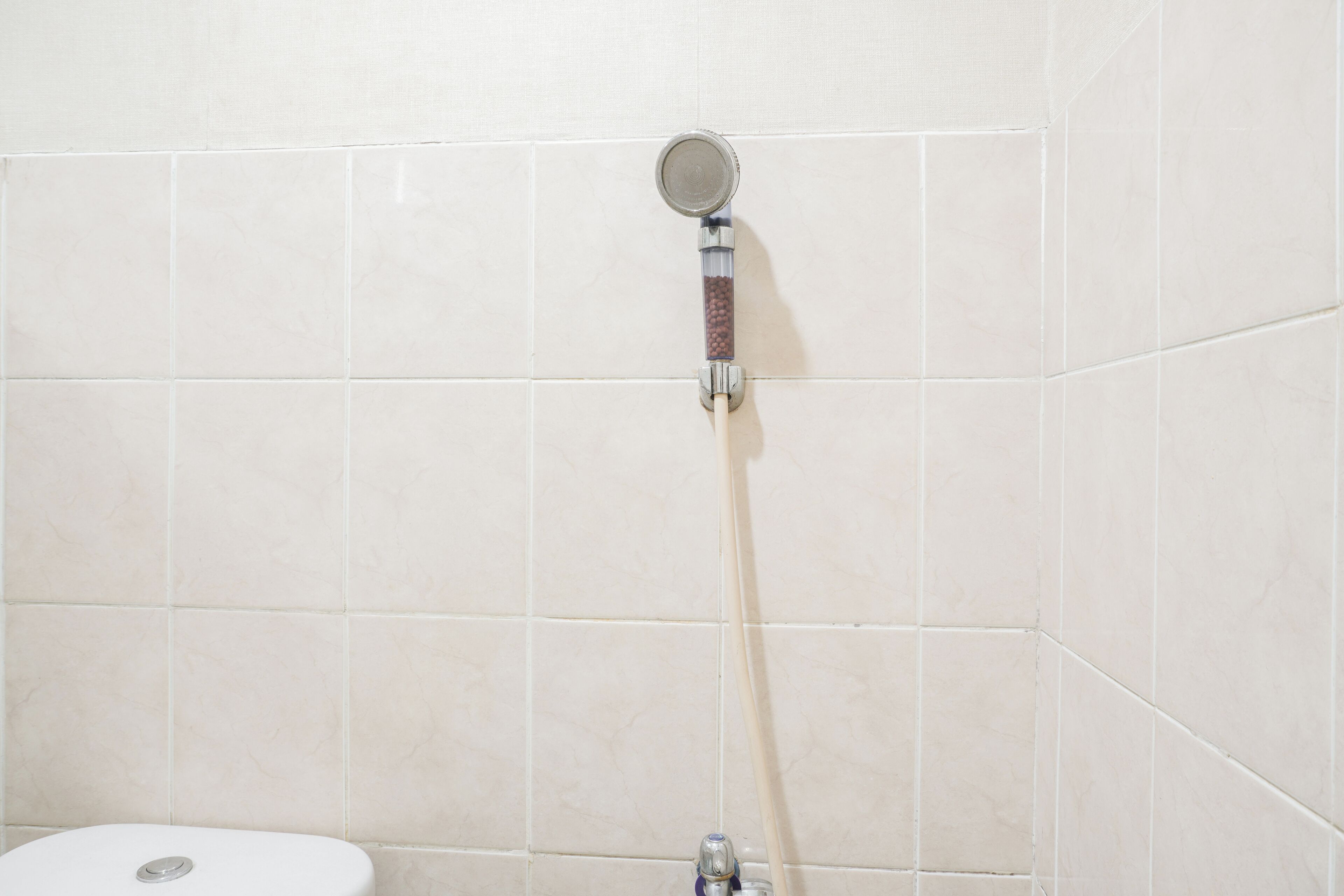 A shower with a handheld showerhead mounted on a tiled wall.