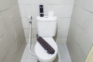 Bathroom features a toilet, toilet paper holder, and bidet attachment.