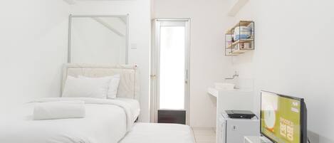 A modern hotel room with a bed, a desk, a television, and a small cabinet.
