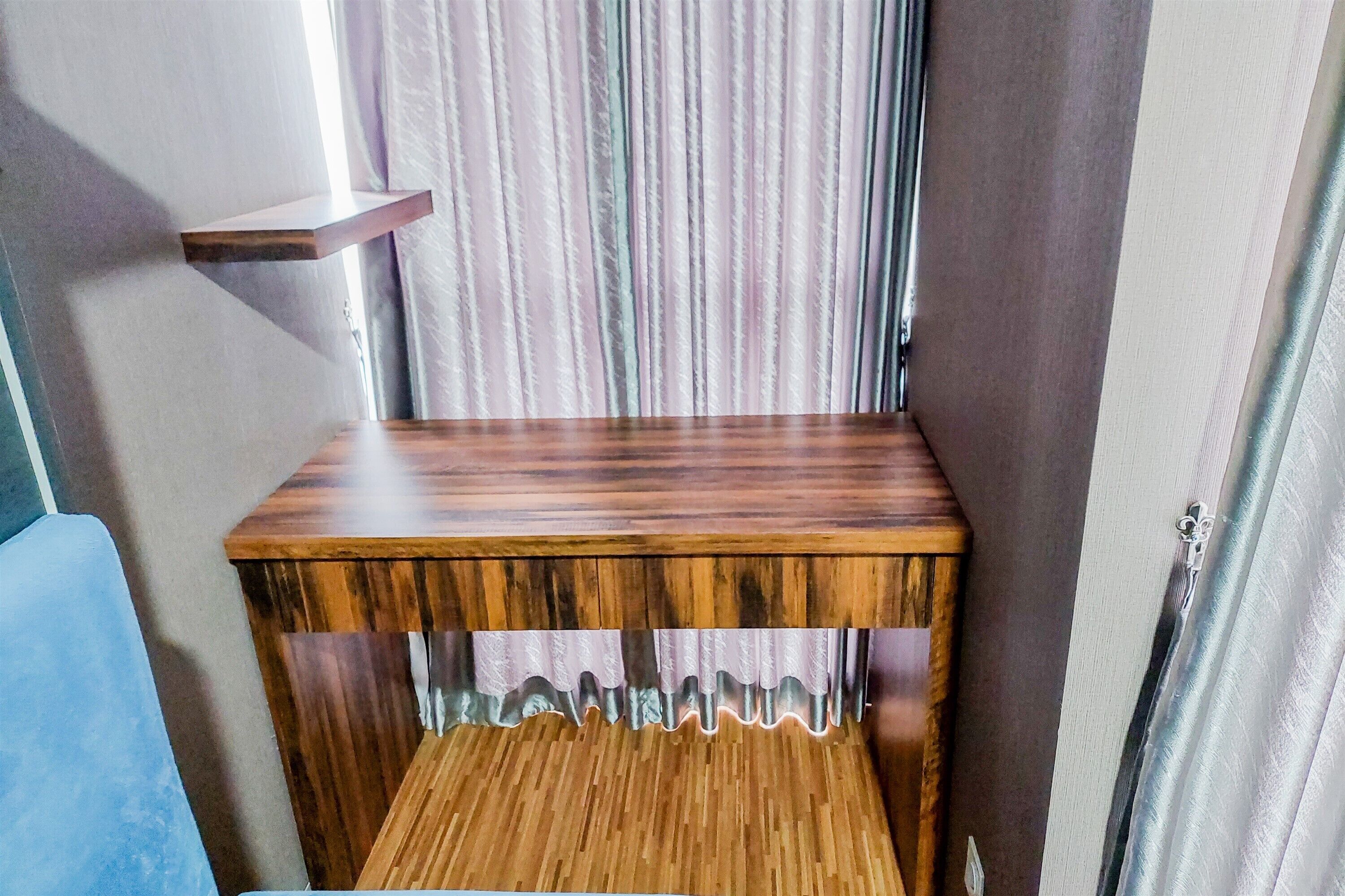 A wooden bench with a slatted design and a shelf on top.