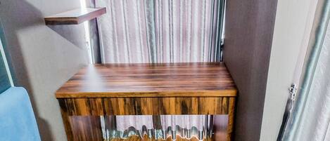 A wooden bench with a slatted design and a shelf on top.