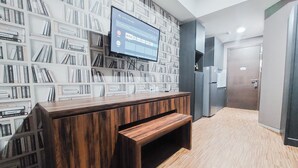 A modern interior with a wooden reception desk, a large bookshelf filled with books, and a television mounted on the wall. - Modern Look Studio Pacific Garden Alam Sutera Apartment (Tangerang)