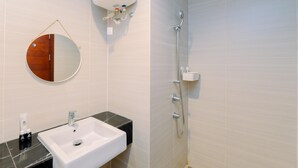 A bathroom with a white sink, a round mirror, and a shower. - Cozy And Warm Studio At West Vista Apartment (Jakarta)