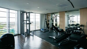 A gym with various exercise equipment, large windows, and a view of greenery.