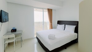 A hotel room with a bed, a desk, and a TV.