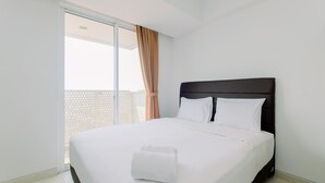 A hotel room with a large bed, a dark headboard, and a view through a sliding glass door.