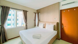 A hotel room with a large bed, a window with curtains, an air conditioning unit, and a door. - Comfort Living 3Br Apartment At 25Th Floor Thamrin Residence (Jakarta)
