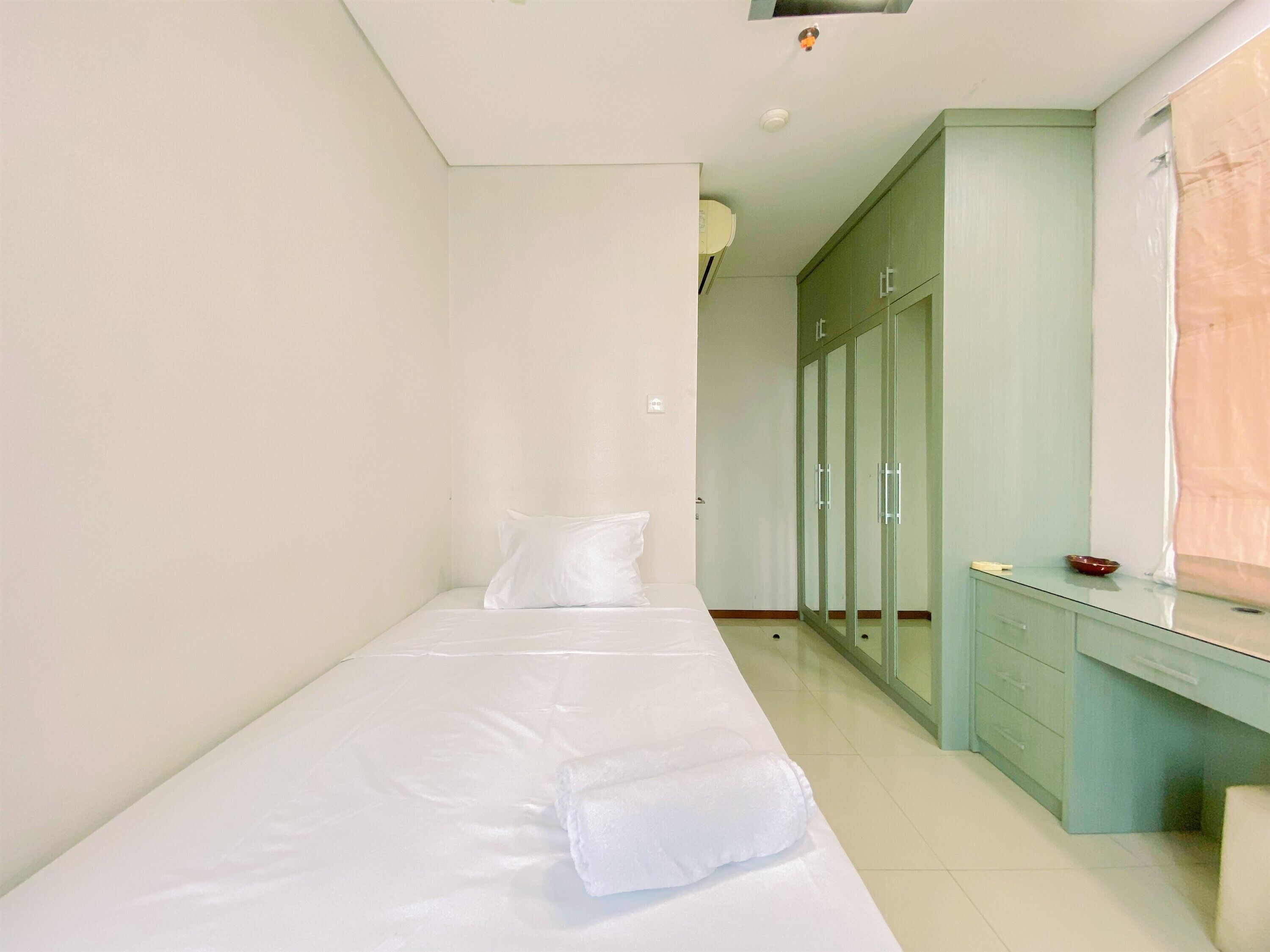 Een slaapkamer met een eenpersoonsbed, een garderobe en een bureau.