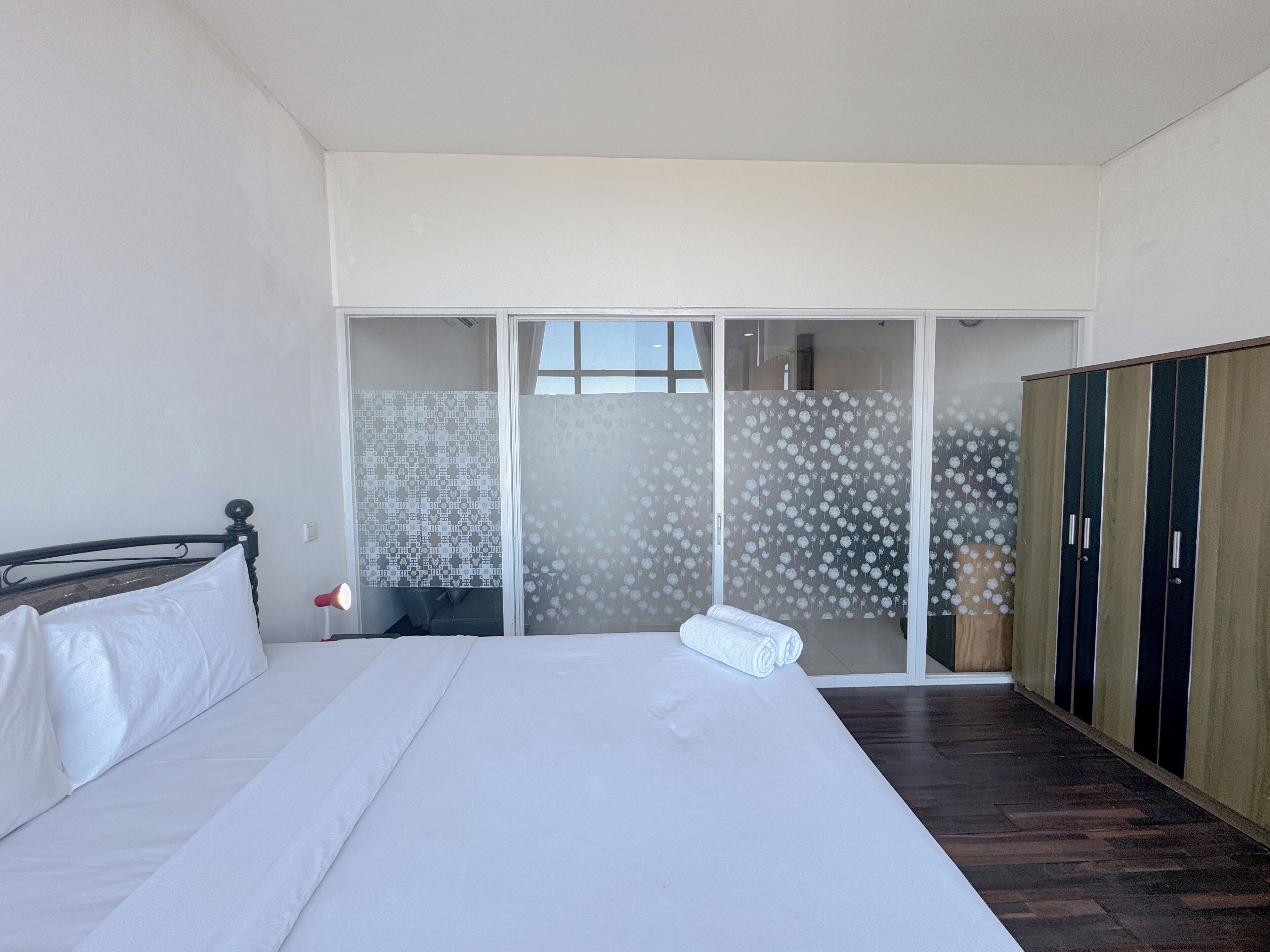 Ein Schlafzimmer mit einem Bett, einem Kleiderschrank und einer Schiebetür mit satinierten Glasscheiben.