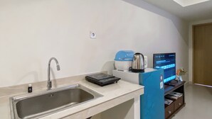 A modern kitchen with a stainless steel sink, a kettle, a coffee maker, and a digital screen displaying a menu.