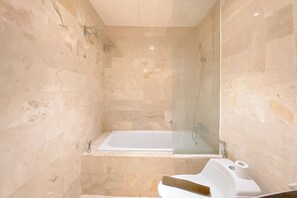 Bathroom features a bathtub, glass-enclosed shower, and a small sink.