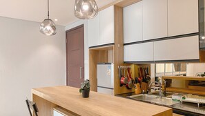 A modern kitchen with wooden countertops, a built-in sink, and hanging utensils. - Wonderful And Homey 1Br Apartment The Empyreal Epicentrum Kuningan (Jakarta)