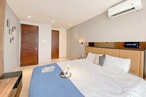 A hotel room with a large bed, a bedside table, a TV, and an air conditioning unit. - Wonderful And Homey 1Br Apartment The Empyreal Epicentrum Kuningan (Jakarta)