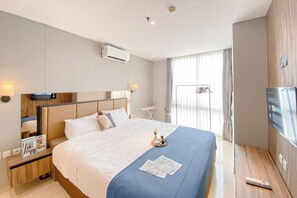 Relax in a spacious room with a large bed, flat-screen TV, and a nightstand with a lamp.