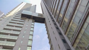 A tall, modern building with a glass facade and a distinctive architectural feature resembling a bridge or overhang. - Wonderful And Homey 1Br Apartment The Empyreal Epicentrum Kuningan (Jakarta)