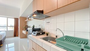 A modern kitchen with wooden cabinets, a stainless steel sink, and a green dish rack.
