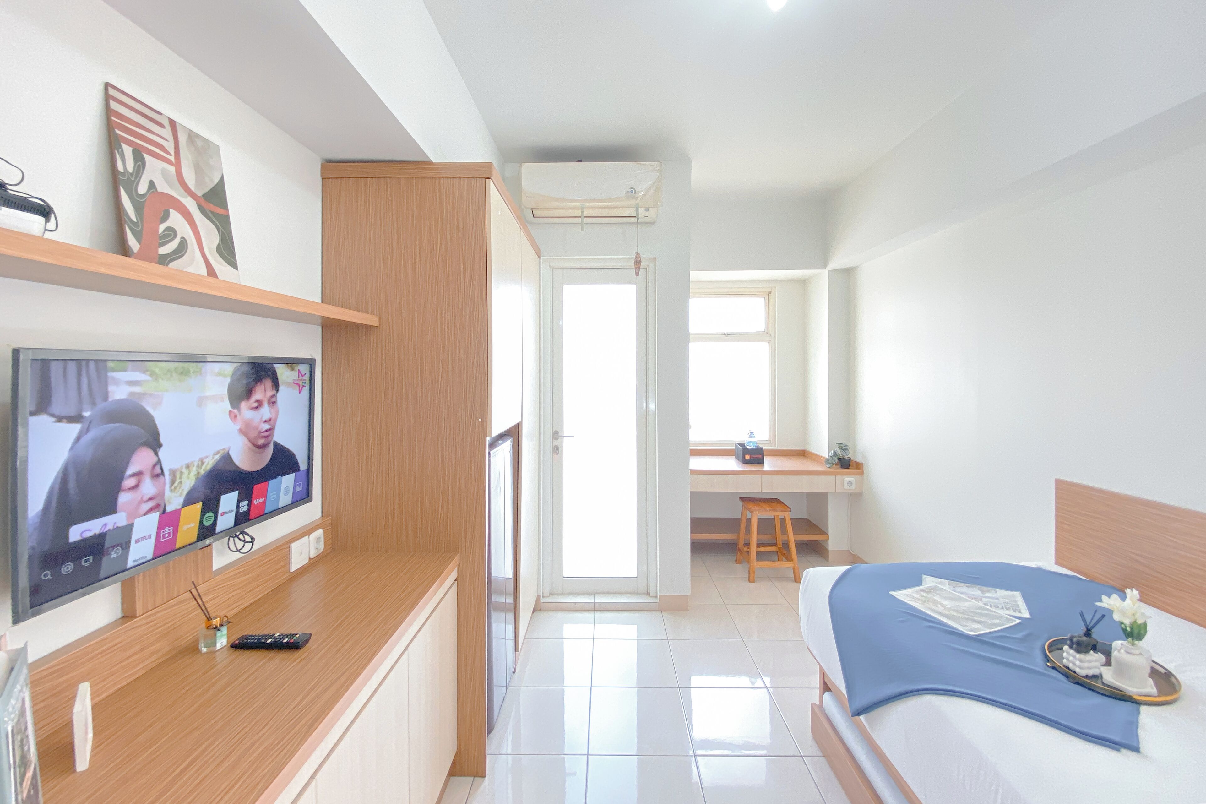 Une chambre d’hôtel moderne équipée d’une télévision, d’un bureau, d’un lit et d’une salle de bain.