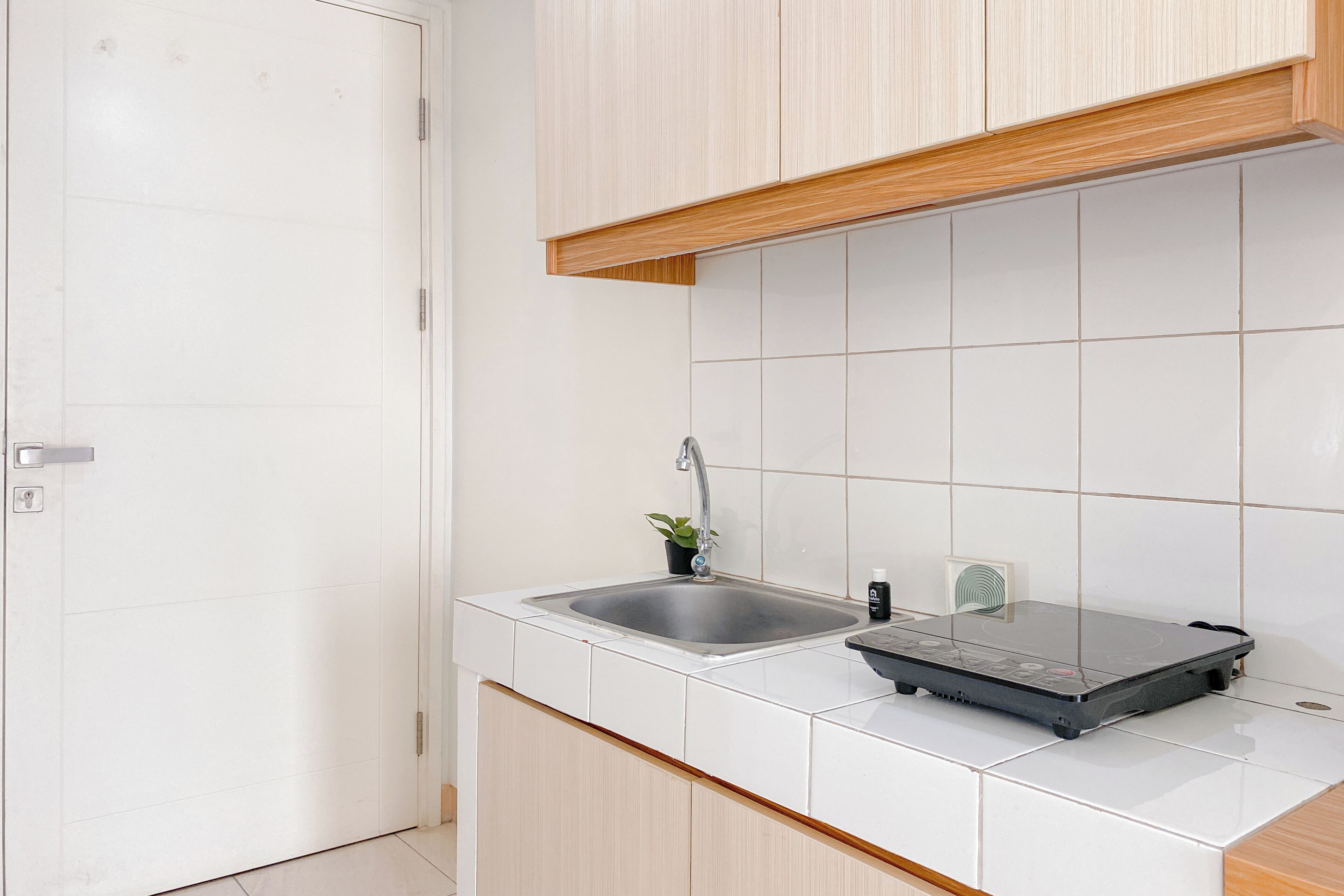 A kitchen with white cabinets, a stainless steel sink, and a portable electric stove.