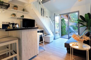 A modern kitchen with a built-in microwave, coffee maker, and toaster. There is a white staircase leading to a balcony with a view of the garden. - Maison Kabâna - Welkeys (Capbreton)