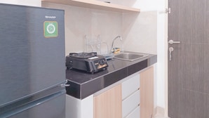 Uma cozinha compacta com geladeira Sharp, fogão a gás e pia.
