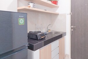 A compact kitchen with a Sharp refrigerator, a gas stove, and a sink.