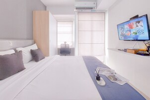 A modern hotel room with a large bed, a flat-screen TV, a desk with a chair, and a window with blinds.