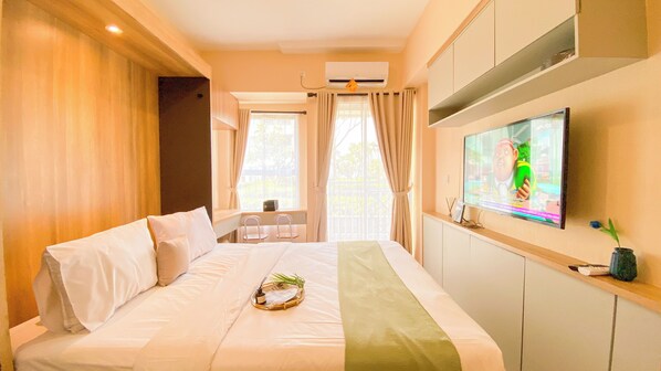 Une chambre d’hôtel avec un lit, une télévision et une fenêtre avec des rideaux.