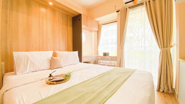 Une chambre d’hôtel avec un grand lit, une table de chevet, une chaise et une fenêtre avec des rideaux.