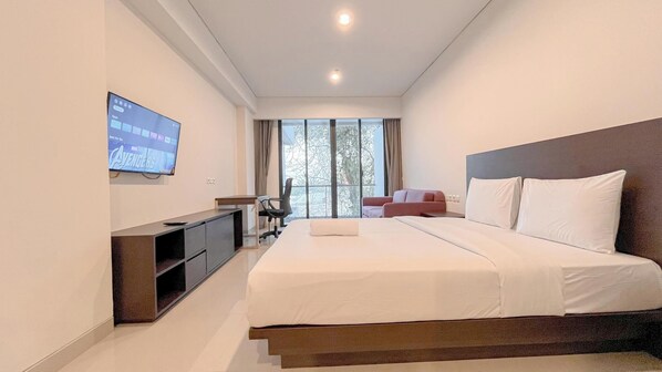 A modern hotel room with a large bed, a TV mounted on the wall, a desk, and a chair. - Studio Near Bali Collection Skales Residence Nusa Dua (Nusa Dua)