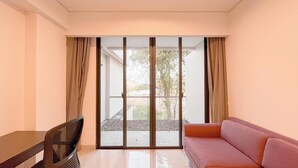 A room with a sofa, a TV, and a sliding glass door leading to an outdoor area. - Modern Look Studio (No Kitchen) Apartment At Skales Residence Nusa Dua Bali (Nusa Dua)
