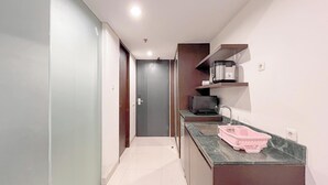 A narrow hallway leading to a door, with a kitchen area on the right featuring a countertop, sink, and a pink dish rack. - Modern Look Studio (No Kitchen) Apartment At Skales Residence Nusa Dua Bali (Nusa Dua)